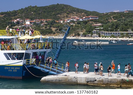 OURANOUPOLI, GREECE - AUGUST 12: Tourists descend from ferry in port of Ouranoupoli village on August 12, 2012 in Ouranoupoli, Greece. Expected records tourist arrivals in Greece for 2013