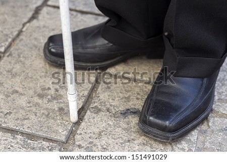 Close up in blind man's feet with stick