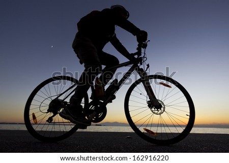 silhouette of the cyclist riding a road bike at sunset