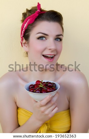 Beautiful woman posing with a cherry, girl giving cherry and promoting healthy food