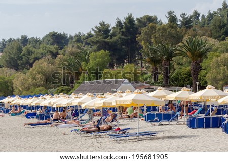 KALLITHEA, GREECE- MAY 26, 2014: Beach with tourists, sun beds and umbrellas. Expected to be the best sea travel destination.View of Kallithea, Halkidiki in Greece.