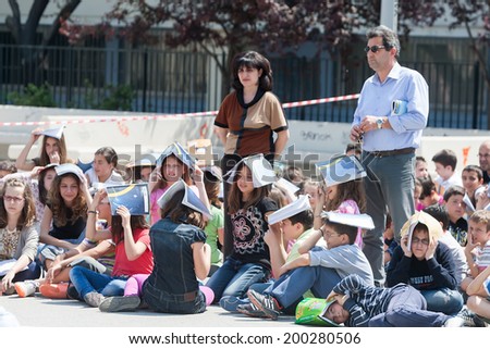 THESSALONIKI, GREECE- APRIL 24, 2013: Children sitting at the school yard, protecting their heads with books. Earthquake exercise, drill. 6th primary school in Thessaloniki, Greece.