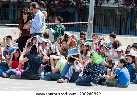 THESSALONIKI, GREECE- APRIL 24, 2013: Children sitting at the school yard, protecting their heads with books. Earthquake exercise, drill. 6th primary school in Thessaloniki, Greece.
