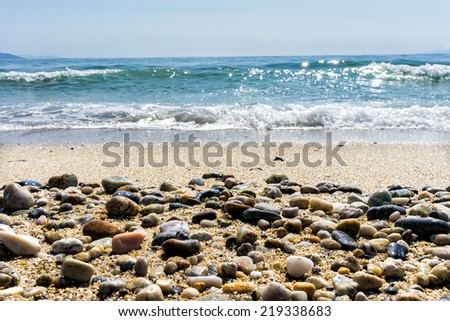 Wave of the sea on the sand beach with sea stones in the front