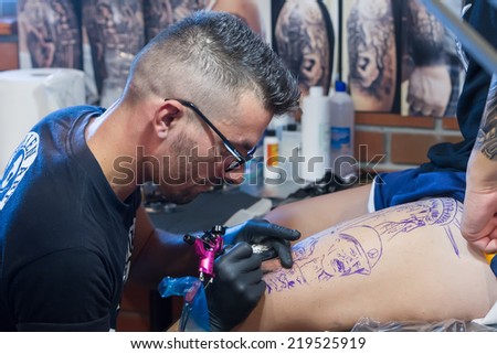 THESSALONIKI, GREECE- SEPTEMBER 19, 2014: Tattoo artist works in The 1st Thessalonink International Tattoo Convention, in Greece. Convention was held in Thessaloniki Port Warehouse C.