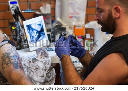 THESSALONIKI, GREECE- SEPTEMBER 19, 2014: Tattoo artist works in The 1st Thessalonink International Tattoo Convention, in Greece. Convention was held in Thessaloniki Port Warehouse C.