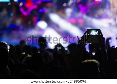 People taking photographs with touch smart phone during a music entertainment public concert