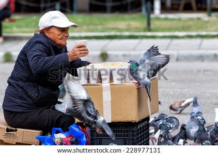 THESSALONIKI, GREECE - OCTOBER 18, 2014: Woman selling seeds for feeding the pigeons in Famous square Aristotelous in Thessaloniki, Greece. Thessaloniki is the second largest city in Greece.