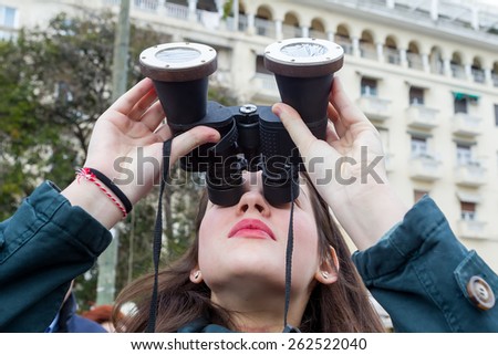 THESSALONIKI, GREECE, MARCH 20, 2015: People use binoculars with special filters to look into the sky at a partial solar eclipse. Over Greece the moon was scheduled to cover approximately 45%.
