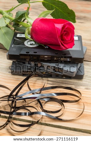 rose and vintage audio cassette on a wooden background.