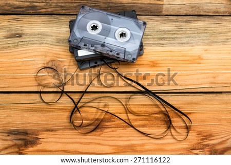 Vintage audio cassettes with loose tape shaping on a wooden background.
