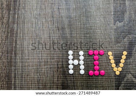 The word HIV(Human Immunodeficiency Virus) written whith pills on a wooden background.