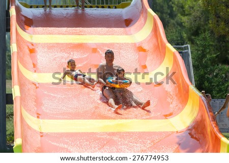 PORTO KARRAS, CHALKIDIKI- JULY 29, 2014: Visitors sliding from the water slide into the pool, having fun on a hot day in summer in Chalkidiki, Greece.