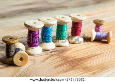 Spools of thread on wooden  background. Old sewing accessories. colored threads