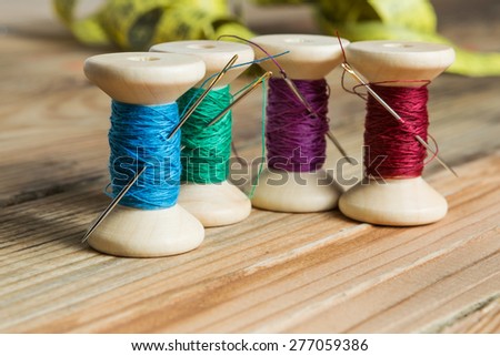 Spools of thread with needles on wooden background. Old sewing accessories. colored threads