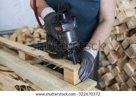 Thessaloniki, Greece, July 8, 2015: Craftsman puts nails in a piece of wood at a woodworking factory in Greece. Wood and furniture production plant, industrial factory with tools and objects.