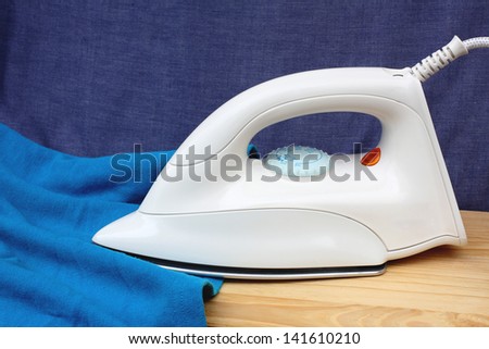 Electric iron and shirt, on white and blue background