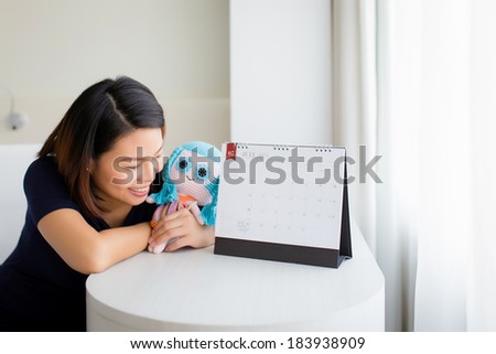 Beautiful pregnant woman looking at the calendar for the date of birth