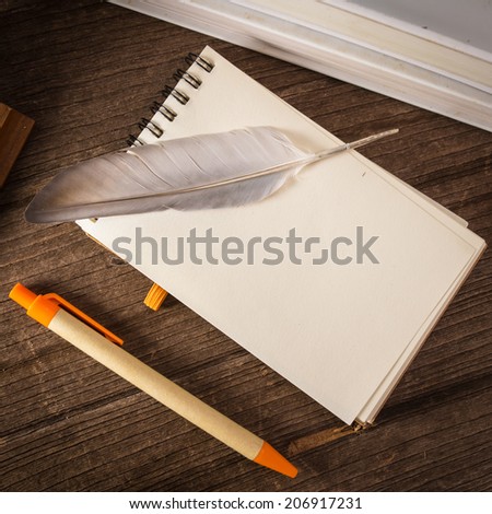 Still life with note and feather pen on wood background