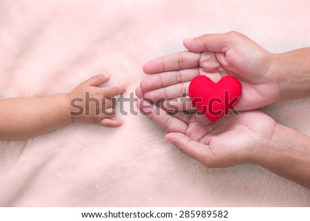 baby and mothers hands made symbol of love.