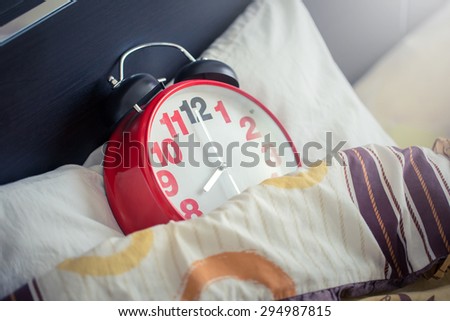 Red alarm clock on the bed in morning,working time