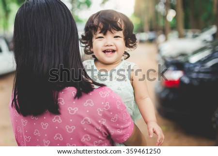 Mom standing in the garden and holding a smiling baby girl