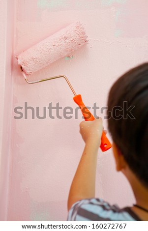 Boy is painting interior wall of home