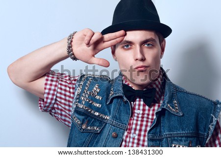 Nice young adult man looking at camera in studio near wall