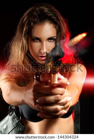 Attractive woman shooting from golden gun in studio