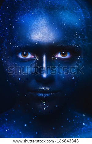 Blue tones portrait of cute woman with dark face art in studio