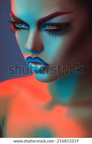 Portrait of beautiful adult woman in red and blue lights and make up in studio