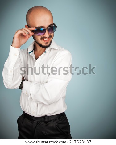 Luxury man in sunglasses and white shirt looking away in studio