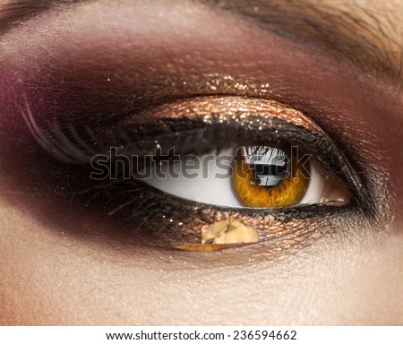 Close up picture of woman brown eye looking away with creative make up in studio