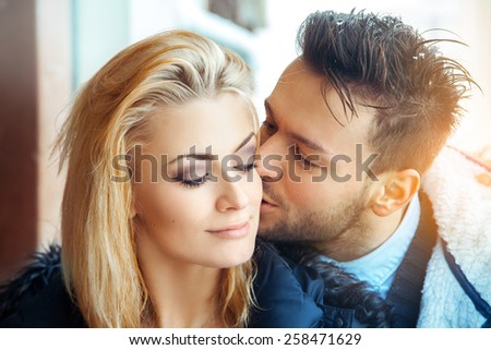Fashion portrait of couple in love. Man kissing his woman in cheek. Horizontal color photo