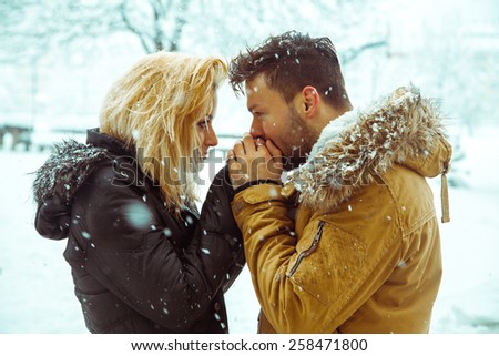 guy kisses the hand of a lady in the snow. horizontal color photo