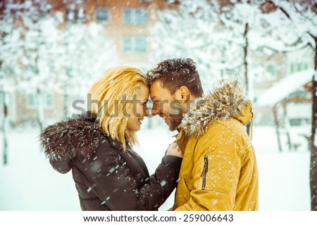 betrothed couple in love looking at each other and smiling in the snow, Horizontal color photo