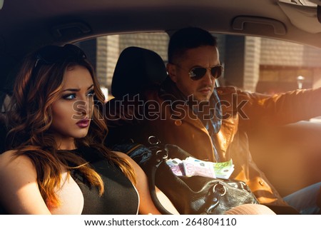 High society sexy couple in car looking away. Inside photo
