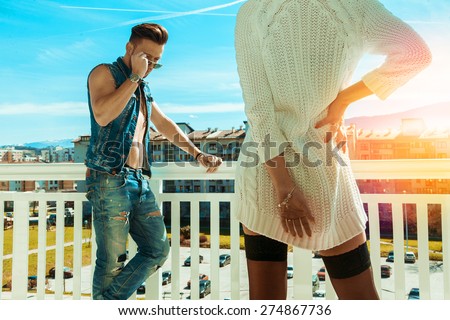 Horizontal photo of sexy fashionable man and seduce woman backside on balcony