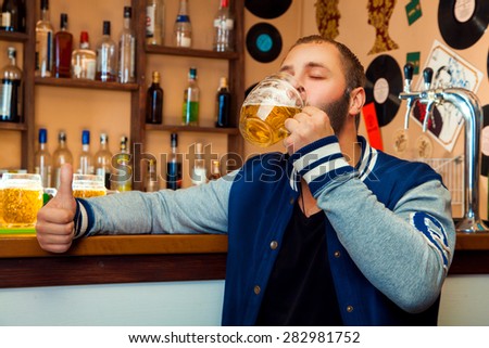 Adult guy in a bar drinking a delicious glass of light beer, horizontal photo