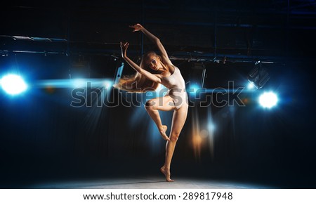 Charming young blonde ballet dancer posing on stage in theater
