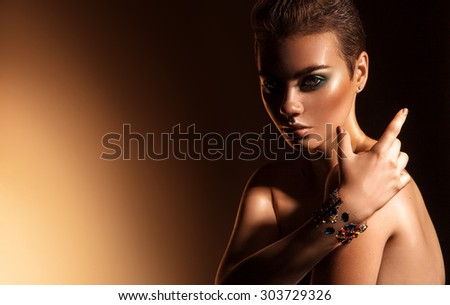 Wonderful young female with green colors makeup and short hairstyle. studio shot. high contrast orange background.