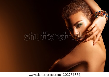 High contrast portrait of charming young woman with makeup and short hairstyle. studio shot. horizontal. high contrast orange background