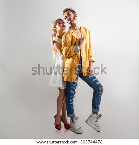 Trendy couple in love. Both with professional makeup. Full length. Gray background. Square.