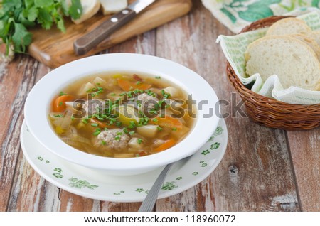 Plate of vegetable soup with meatballs on the wooden table