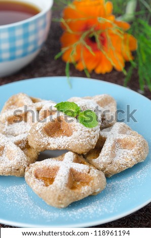 Waffles sprinkled with powdered sugar and black tea closeup selective focus