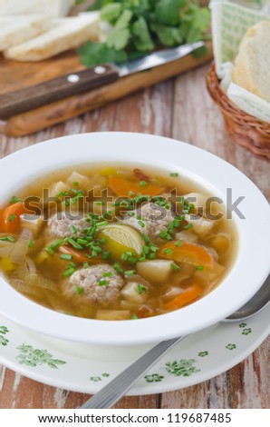 Plate of vegetable soup with meatballs on the wooden table vertical