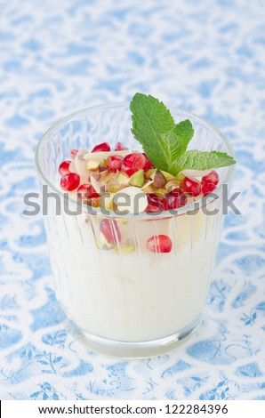 semolina dessert with pomegranate seeds and pistachios garnished with mint in a glass beaker