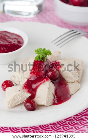 boiled chicken breast with cranberry sauce and a bowl of sauce on the plate