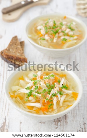 two bowls of vegetable soup with chicken, cabbage and parsley