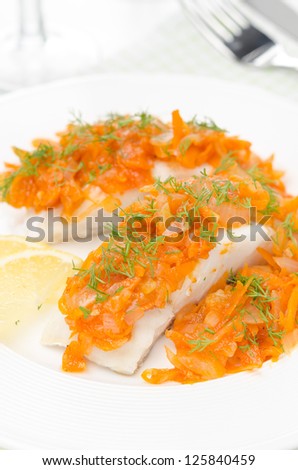 cod with pickled carrot and onion on a white plate, closeup